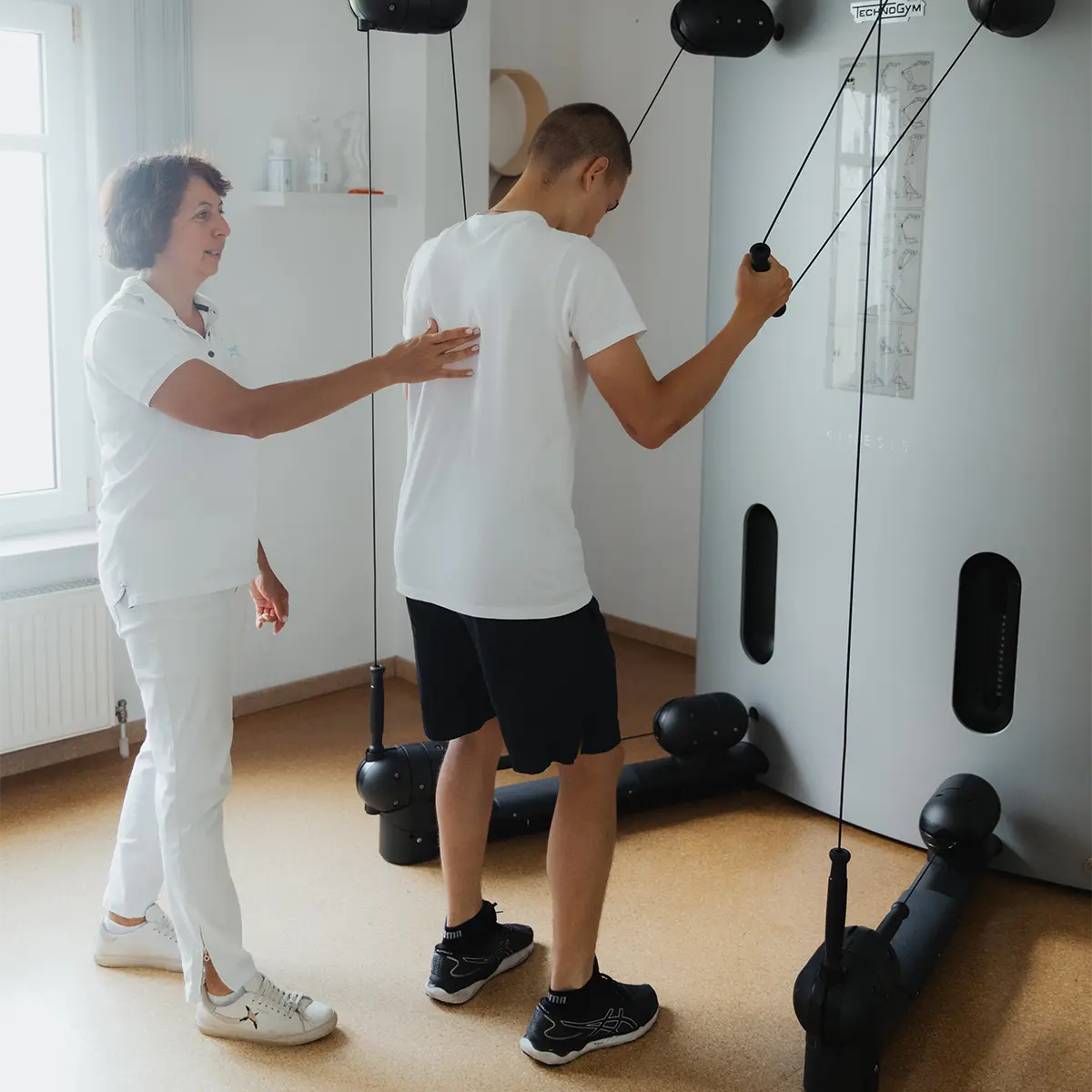 Physiotherapeutin begleitet einen Patienten beim Training am Seilzug