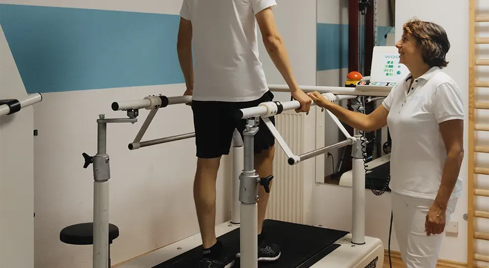 Physiotherapeutin begleitet einen Patienten beim Training am Therapielaufband