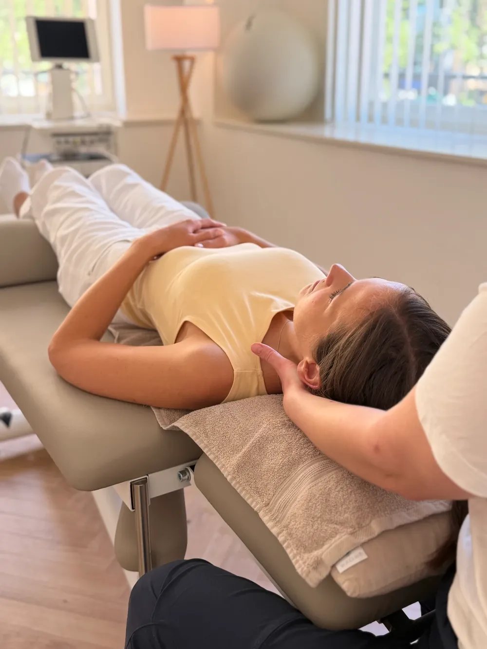Manuelle Therapie in der Praxis Eden Physiotherapie München: Eine entspannt liegende Patientin wird an Nacken und Halswirbelsäule behandelt