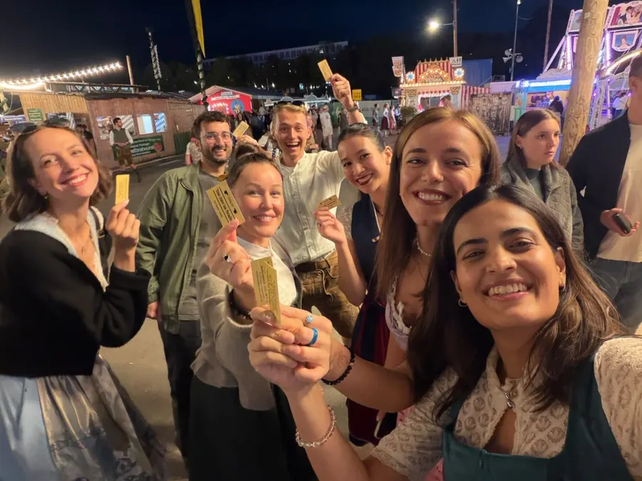 Team von Eden Physiotherapie München beim gemeinsamen Abend auf dem Volksfest – in Tracht und mit gelben Wertmarken in den Händen