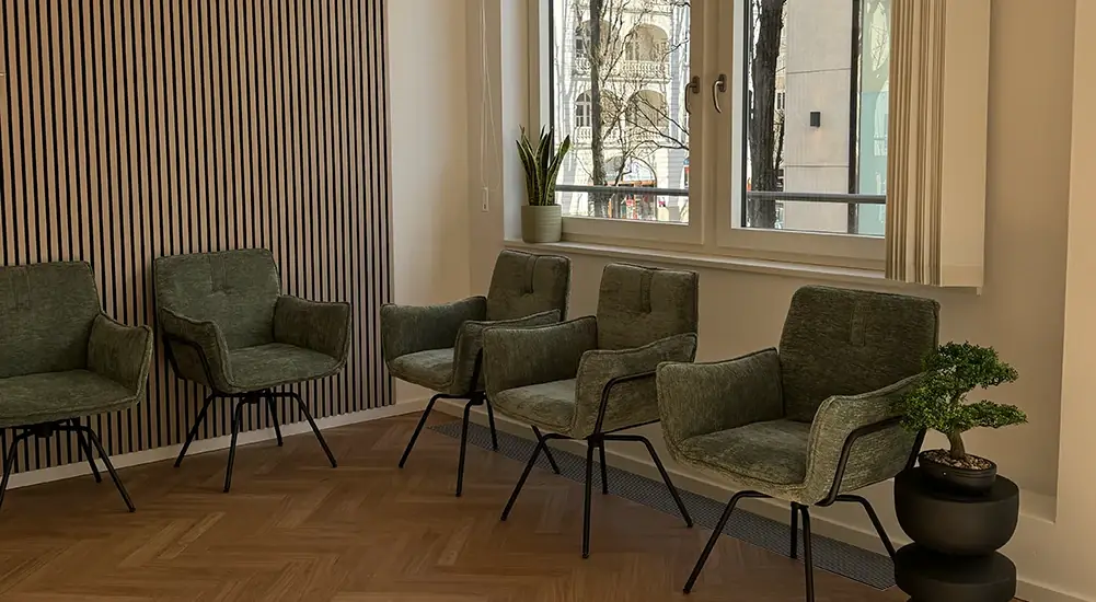Wartebereich mit grünen Sesseln und großen Fenstern