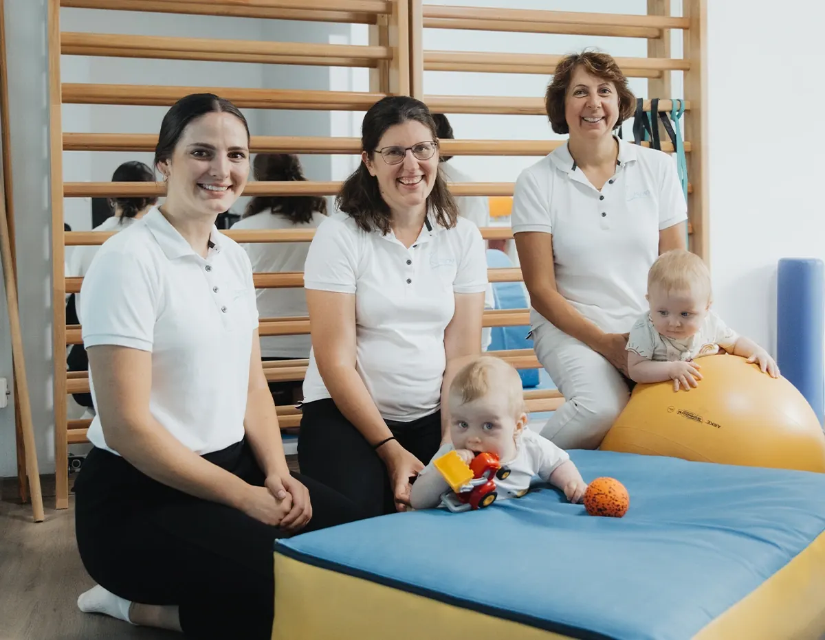 Drei Physiotherapeutinnen von Eden Physiotherapie mit einem Baby im Bewegungsraum